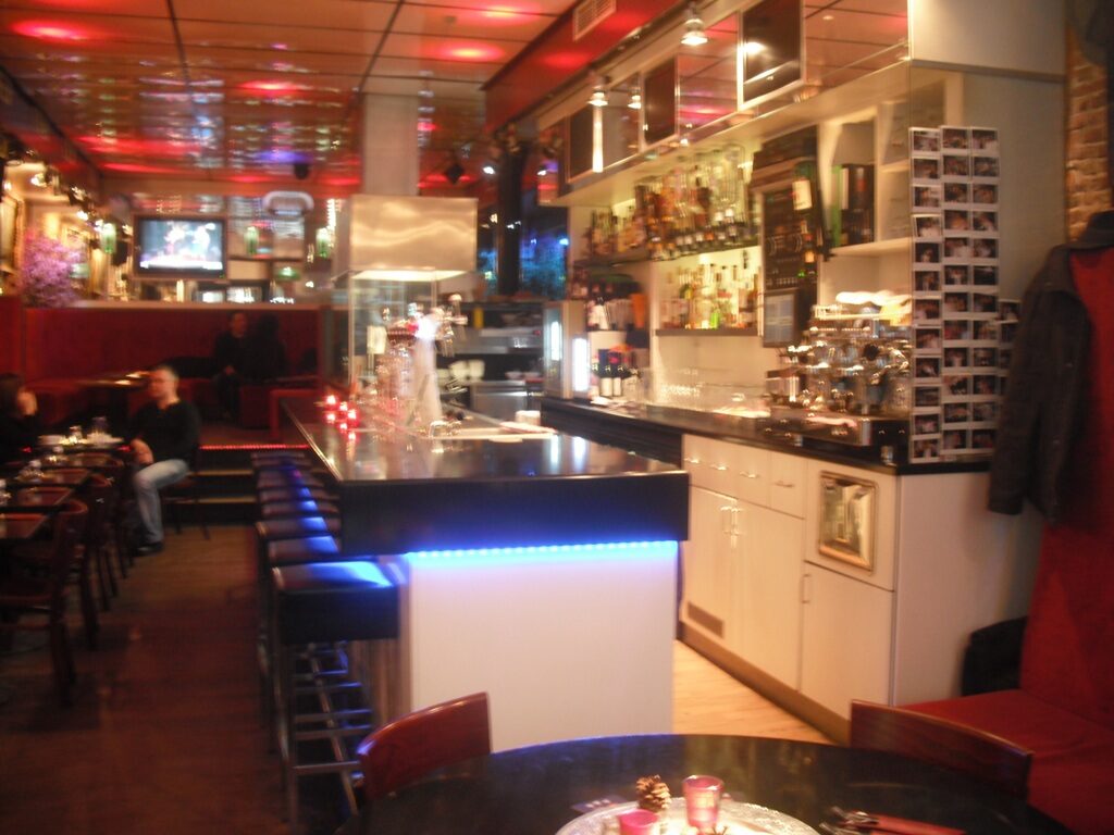 Het café met bar, rode banken en tafels